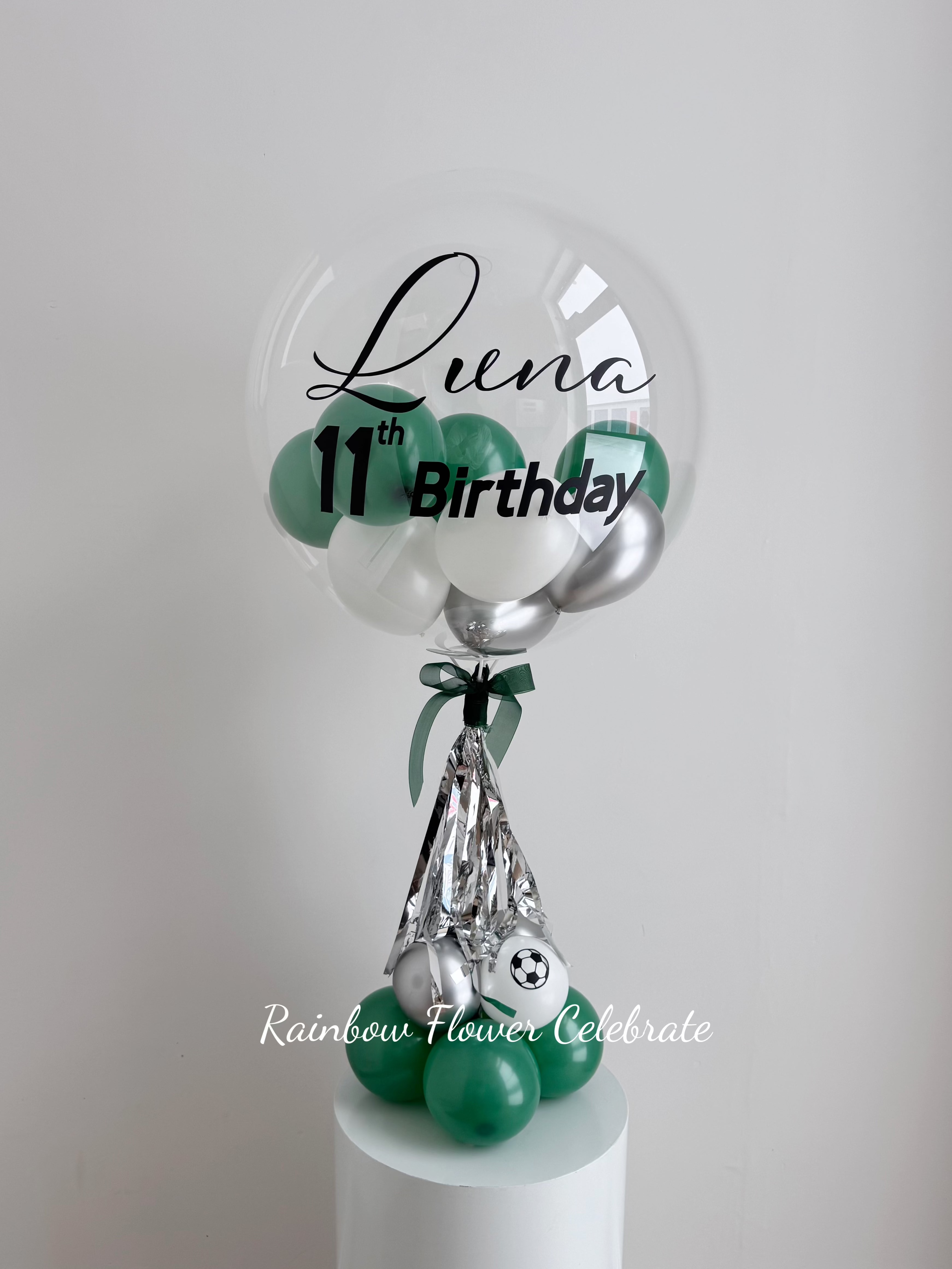 Decorative green, white and silver balloon with personalized Luna 11th birthday on a clear balloon with mini balloon inside, great for table top and centerpiece balloon decoration for birthday.