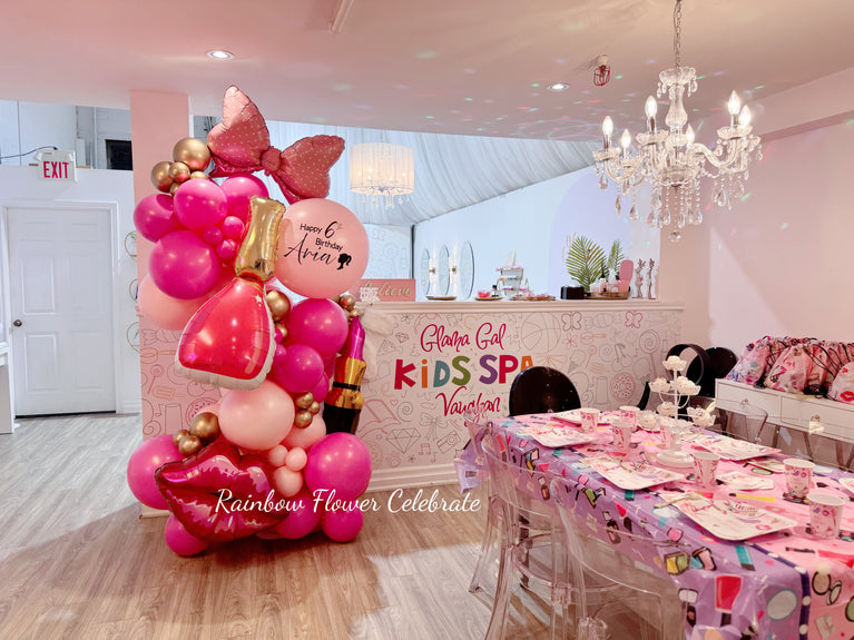 Pink birthday balloon display with makeup-themed decorations at kids spa party setup