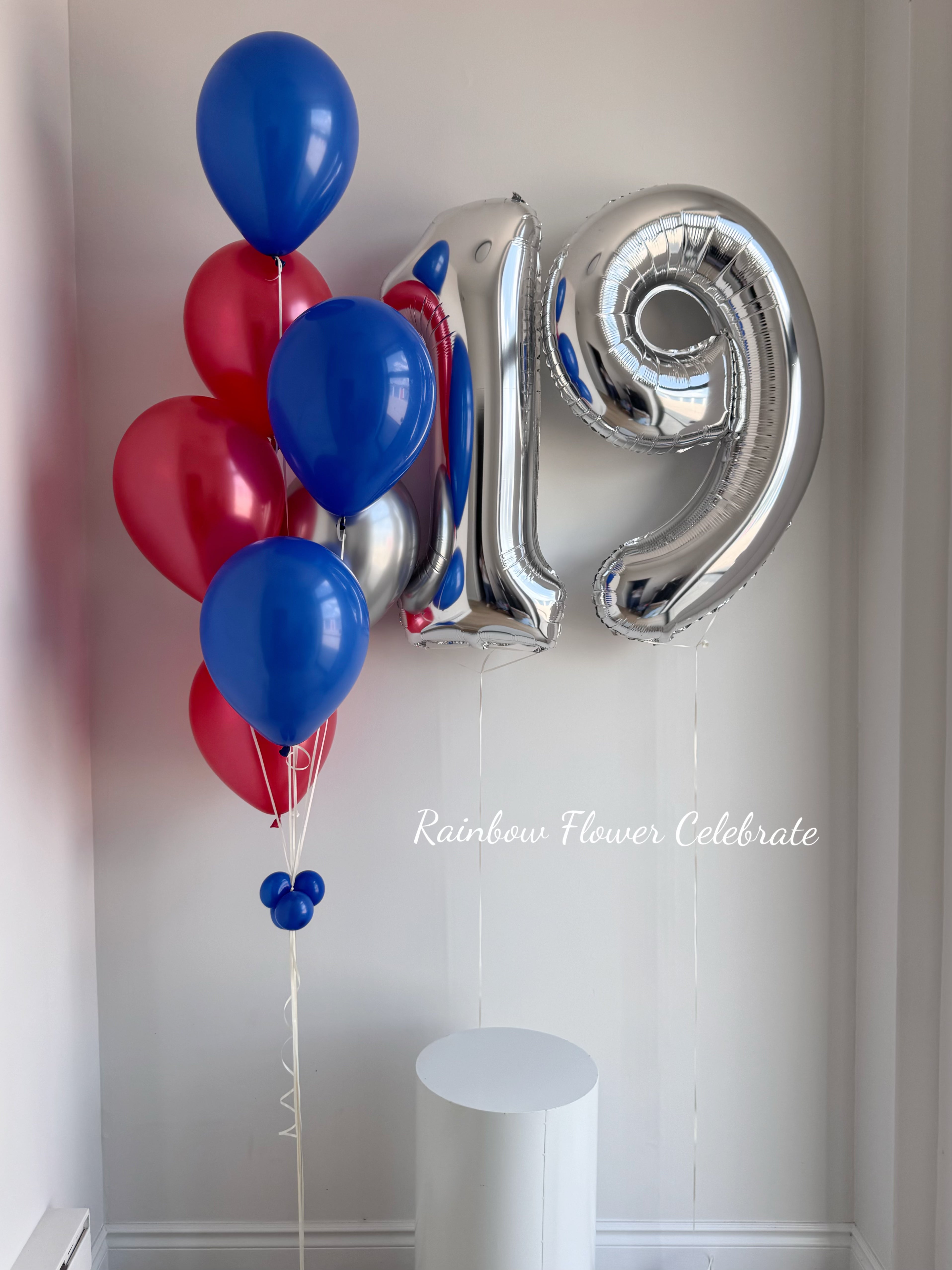 Silver number 19 balloon and red and blue balloons against a white wall.