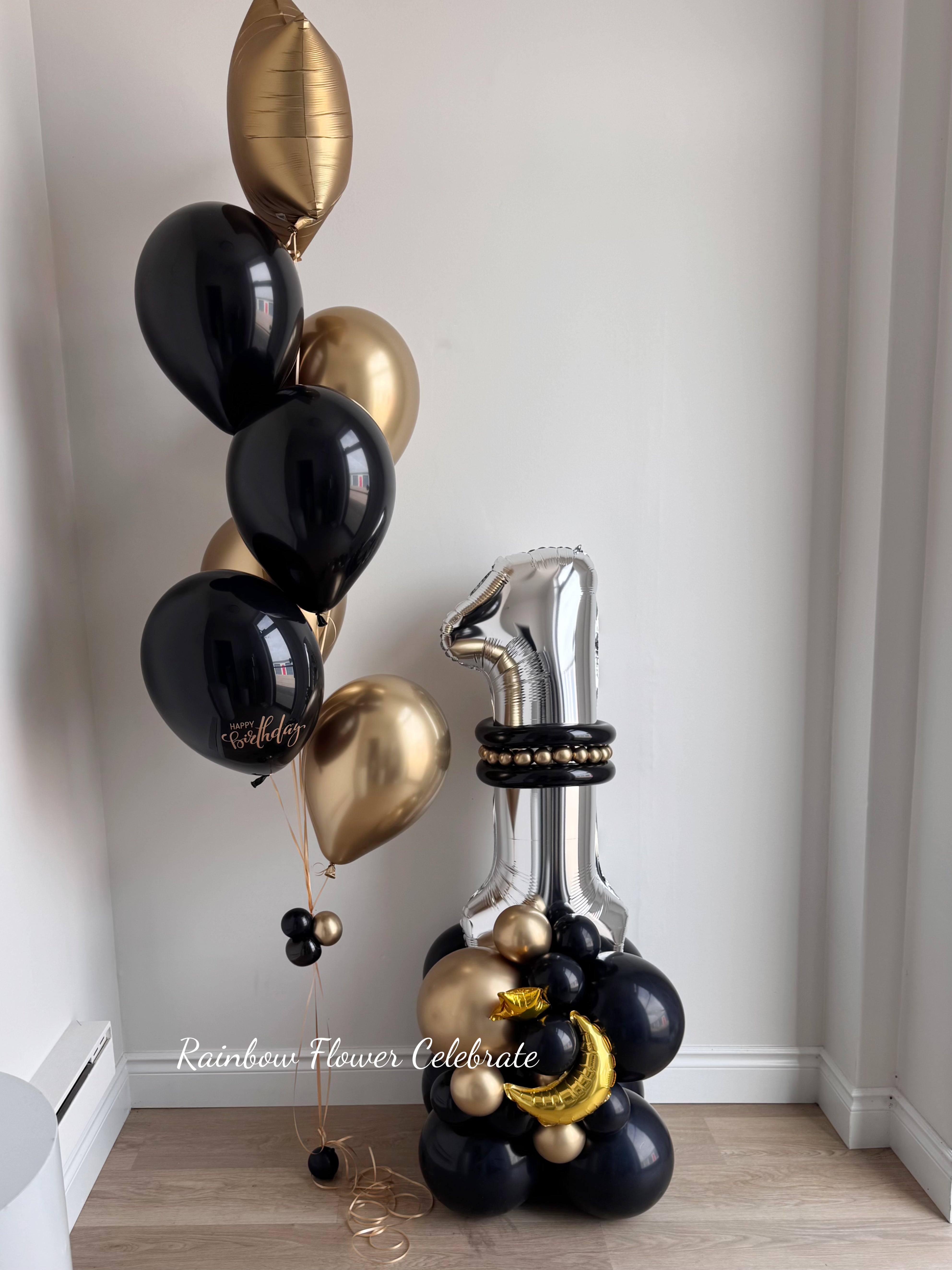 Decorative arrangement of black and gold balloon base with a silver foil number 1 on top combine with a black and gold helium bouquet on side. 