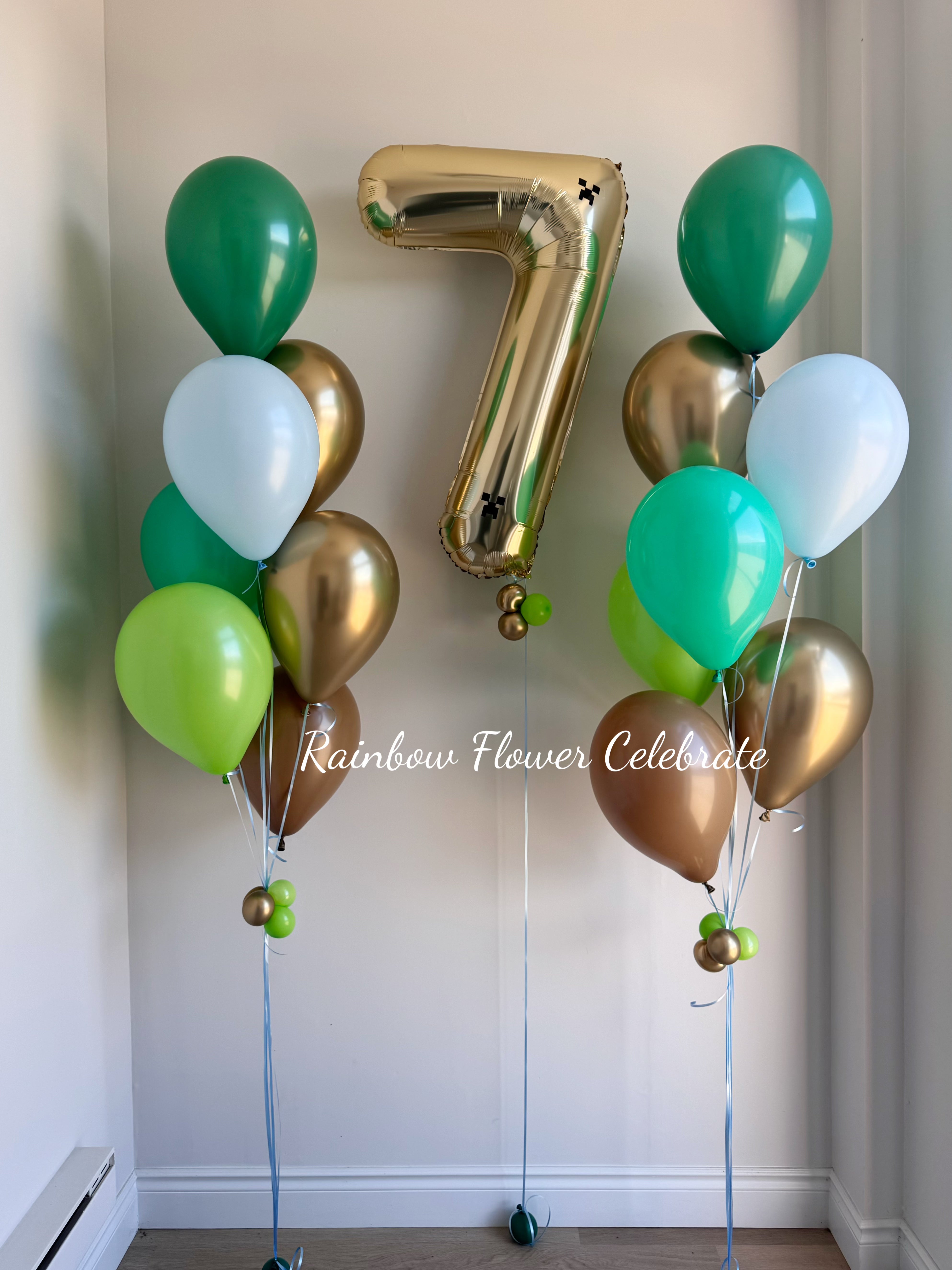 Balloon arrangement with gold, green, and white balloons and a large gold number 7 